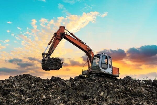 Excavation Contractor Insurance - Stylized Image of an Excavator Working at Construction Site on Summer Day at Sunset